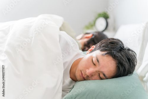 ベッドで眠る若い夫婦（快眠・安眠・熟睡） 