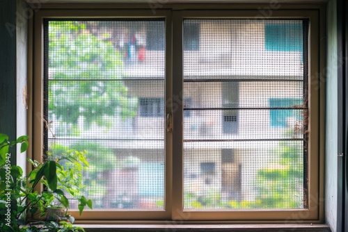 Window with Mesh Screen Overlooking Apartment Complex
