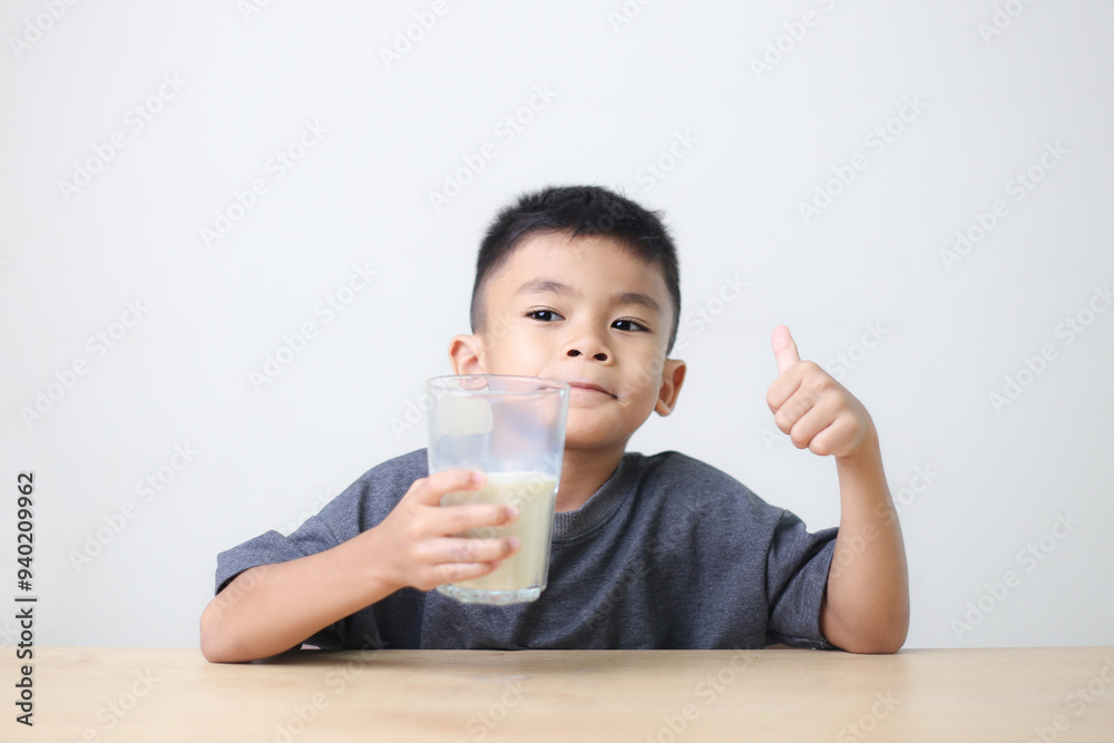 Asian child drinking milk on white background. Smiling of Asian boy with a glass of milk. Asian child drinking milk on white background. Smiling of Asian boy with a glass of milk.