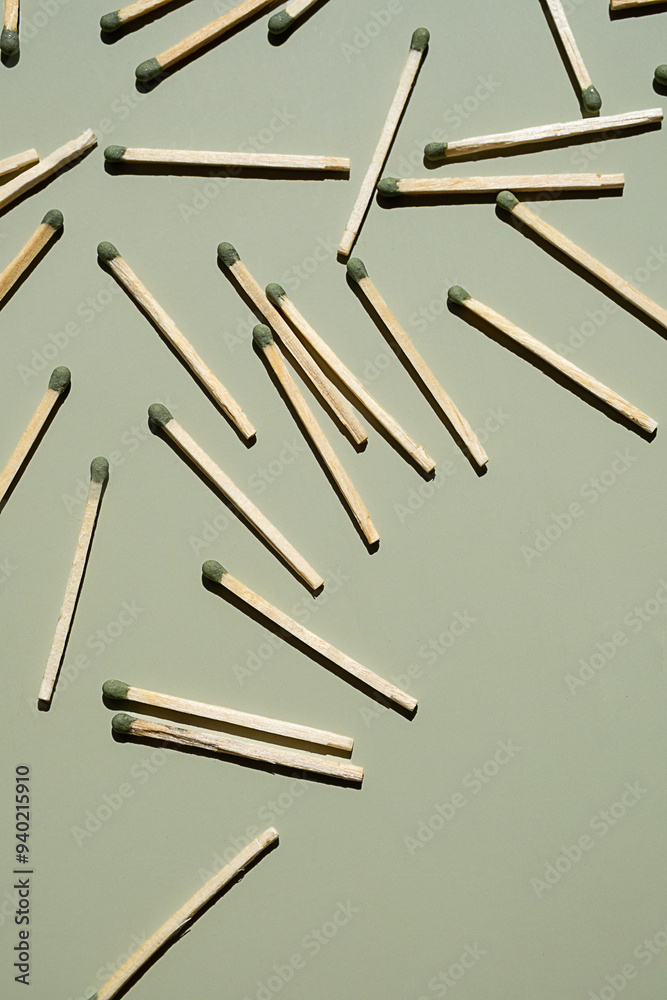 Wooden matchsticks with green tips scattered on light green surface. Wooden matchsticks with green tips scattered on light green surface.