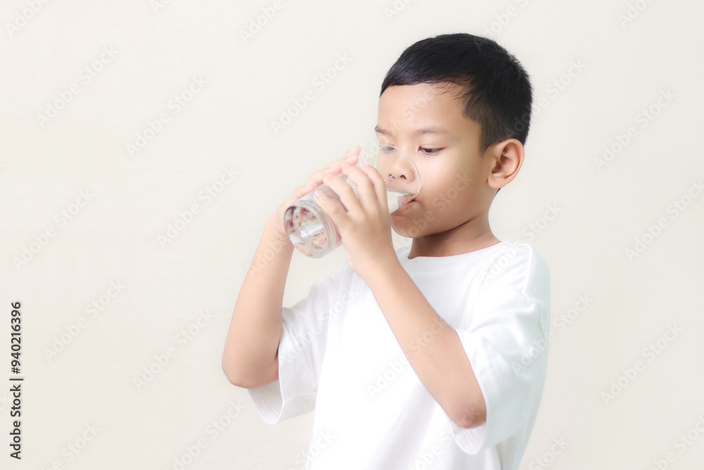cute little asian boy Standing and Smiling little with a holding an empty glass of water on white background. cute little asian boy Standing and Smiling little with a holding an empty glass of water on white background.