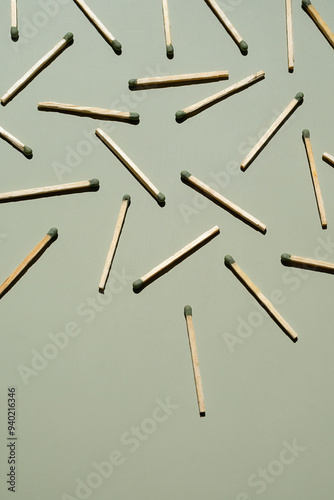 Wooden matchsticks with green tips scattered on light green surface.