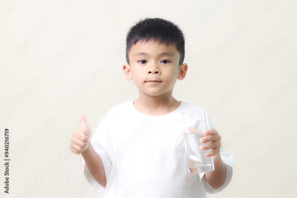 cute little asian boy Standing and Smiling little with a holding an empty glass of water on white background. cute little asian boy Standing and Smiling little with a holding an empty glass of water on white background.