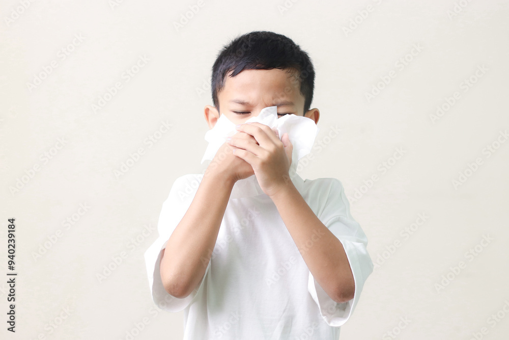 Little asian boy sick and sad with sneezing on nose and cold cough on tissue paper becauseweak or virus and bacteria. cold allergies or illness, health,