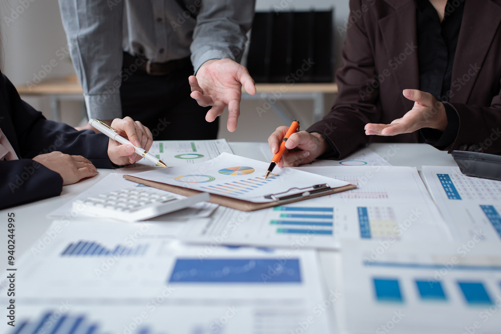 Group of confident business people point to graphs and charts to analyze market data, balance sheet, account, net profit to plan new sales strategies to increase production capacity. Group of confident business people point to graphs and charts to analyze market data, balance sheet, account, net profit to plan new sales strategies to increase production capacity.