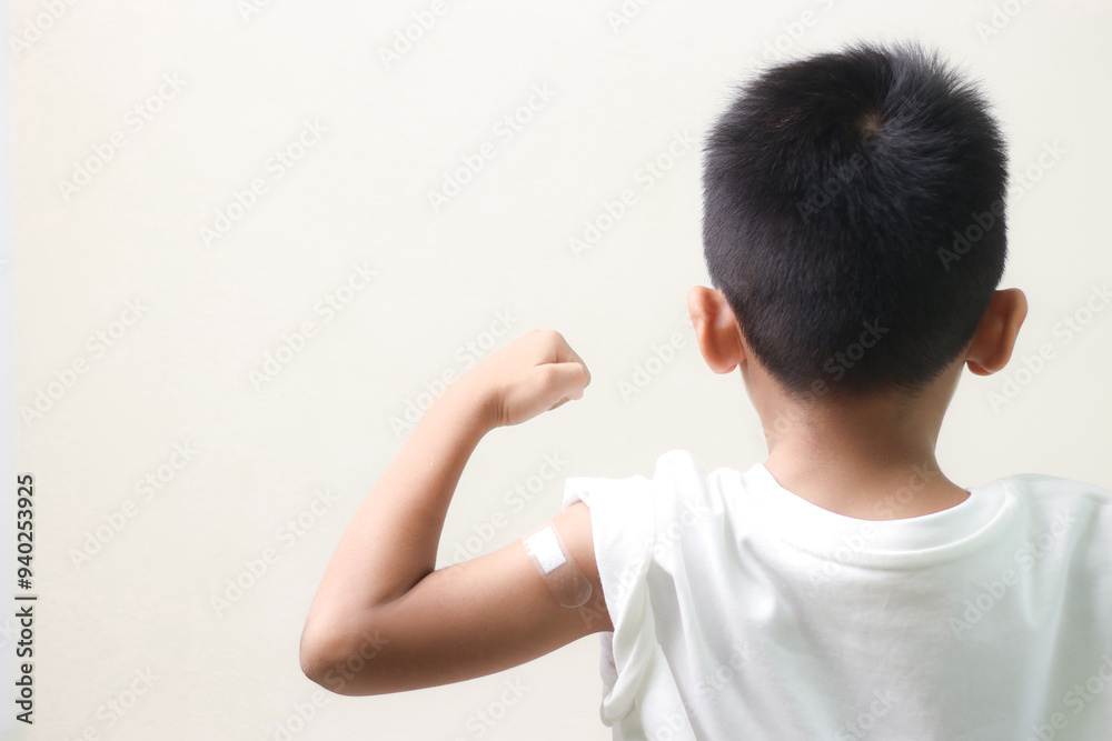 Little asian child boy with bandage plaster on her arm after Covid-19 vaccination. Injection covid vaccine, healthcare for children. Little asian child boy with bandage plaster on her arm after Covid-19 vaccination. Injection covid vaccine, healthcare for children.