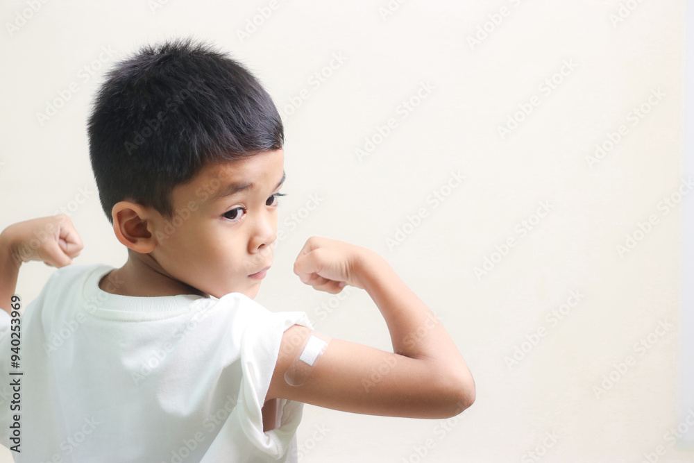 Little asian child boy with bandage plaster on her arm after Covid-19 vaccination. Injection covid vaccine, healthcare for children. Little asian child boy with bandage plaster on her arm after Covid-19 vaccination. Injection covid vaccine, healthcare for children.