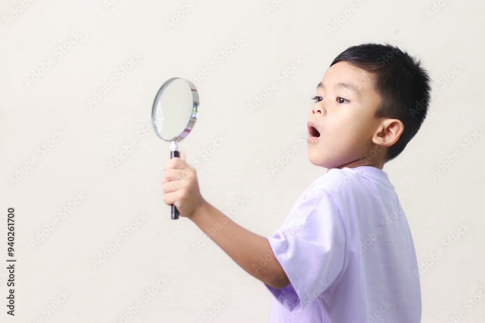 Portrait of surprised cute little asian boy looking through a magnifying glass. Education concept. Portrait of surprised cute little asian boy looking through a magnifying glass. Education concept.