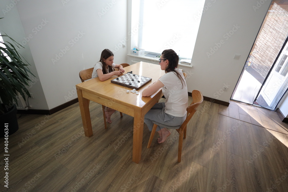 Mother and daughter playing chess at home Mother and daughter playing chess at home