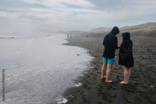 Poeple playing at the waters edge on the beach at Muriwai, Auckland, New Zealand. photo