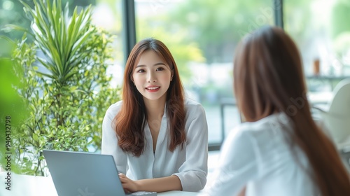 An asian female HR manager interviewing a job candidate in his office.