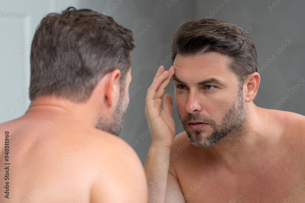 Middle aged hispanic man looking in mirror, facial skin and stubble. Male beauty care product. Skincare, home spa. Beauty portrait of a beautiful man. Spa model, moisturizing nourishing creme. Middle aged hispanic man looking in mirror, facial skin and stubble. Male beauty care product. Skincare, home spa. Beauty portrait of a beautiful man. Spa model, moisturizing nourishing creme.