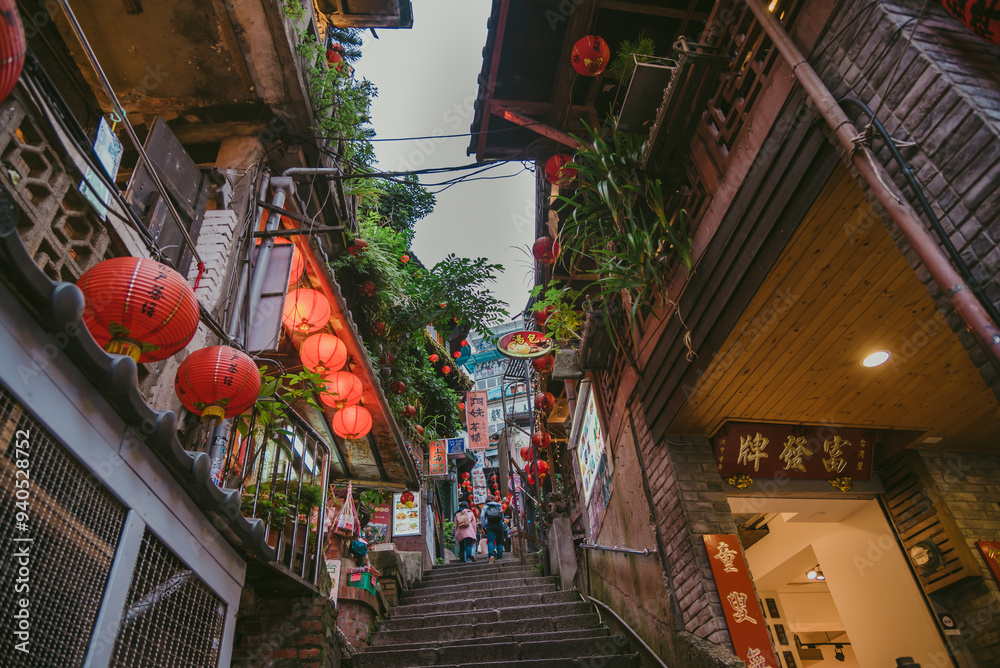Obraz premium Jiufen Old Street is a narrow, winding alleyway with shops, teahouses, and restaurants that offers tourists a view of traditional Taiwanese life.