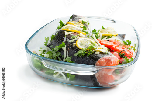 Raw trouts fish on the baking dish with tomatoes and lemon isolated on white