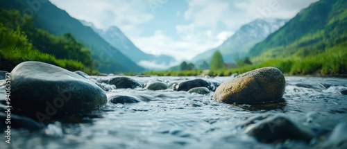  A river dotted with mid-stream rocks, mountain range in the distance with tree-dotted hills and grassy foreground photo