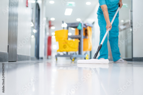 A cleaner in uniform using mops cleaning hall floor at patient room the hospital epoxy floor. photo