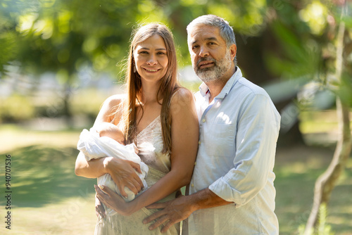 Happy family posing with newborn baby in park