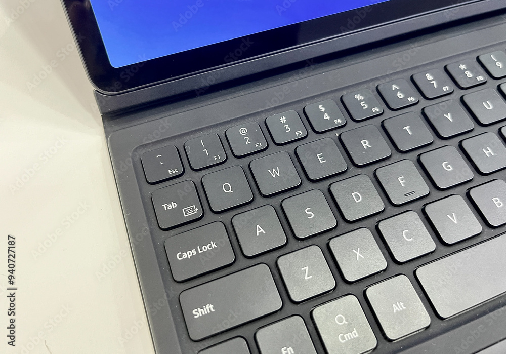 Tablet attached to gray colored keyboard. Modern gadget isolated on horizontal white desk surface background. Tablet attached to gray colored keyboard. Modern gadget isolated on horizontal white desk surface background.