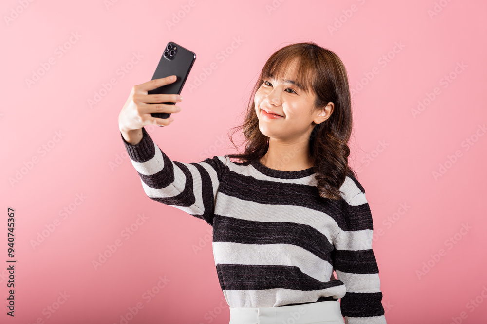 © sorapop - Happy Asian portrait beautiful cute young woman smiling excited making selfie photo, video call on smartphone studio shot isolated on pink background, female hold mobile phone raise hand say hello © sorapop - Happy Asian portrait beautiful cute young woman smiling excited making selfie photo, video call on smartphone studio shot isolated on pink background, female hold mobile phone raise hand say hello