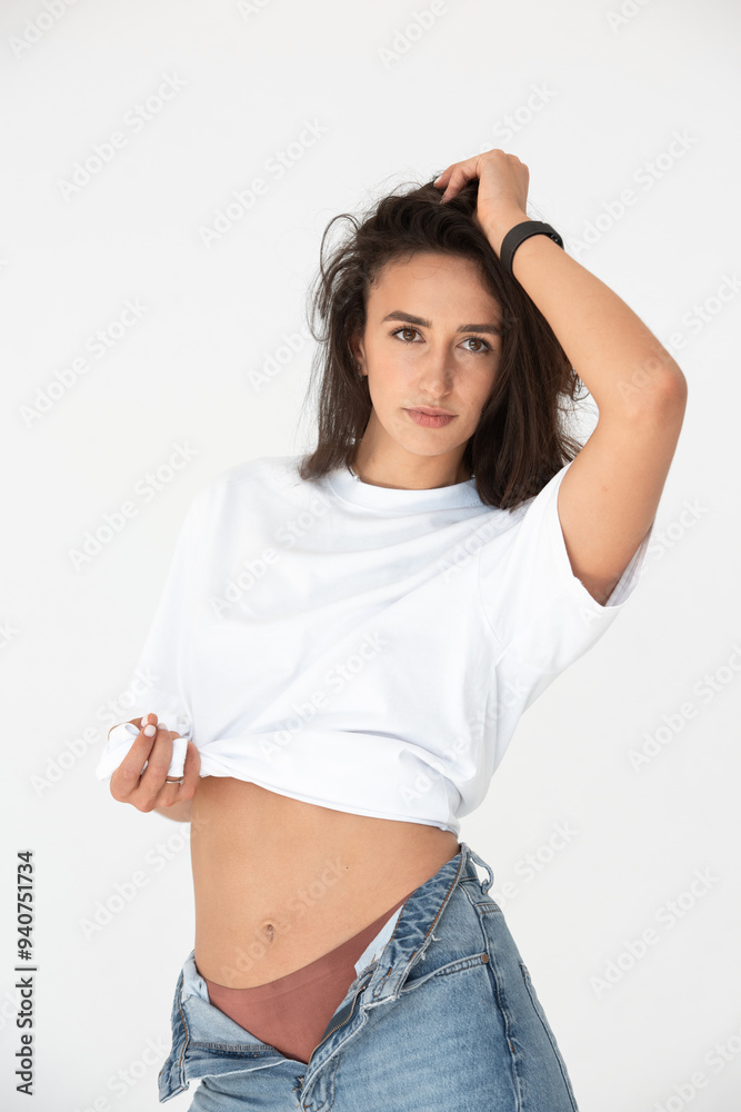 Happy beautiful girl posing in a new hot summer look. Wearing blue jeans and white t-shirt Happy beautiful girl posing in a new hot summer look. Wearing blue jeans and white t-shirt
