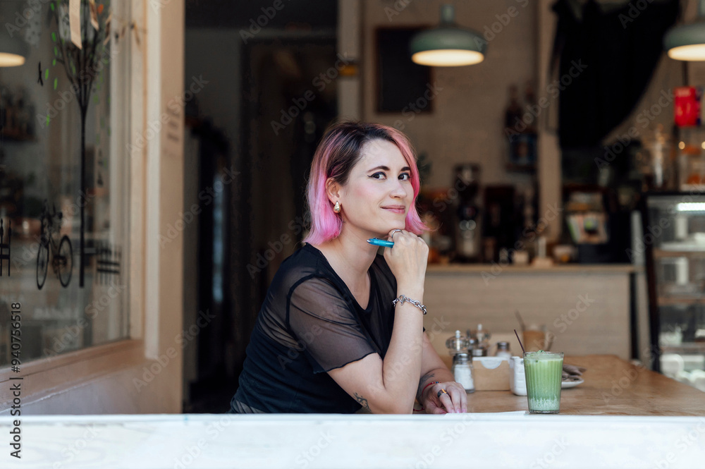 Smiling hipster woman leaning on elbow and sitting in cafe Smiling hipster woman leaning on elbow and sitting in cafe