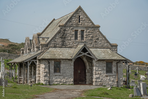 Great Orme Cemetery Chapel, Llandudno, a pretty stone-built medieval church standing amongst many grave stones in a cemetery