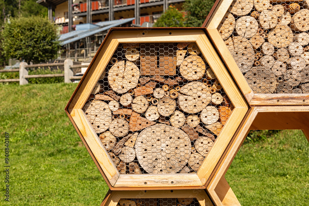 Wooden insect house or bee hotel in the Alps town. Wood Bugs hotel in spring backyard, nest sites for solitary bees, wasps, butterflies, ladybug. Wooden insect house or bee hotel in the Alps town. Wood Bugs hotel in spring backyard, nest sites for solitary bees, wasps, butterflies, ladybug.