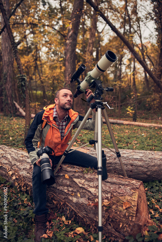 man using telescope for bird and animal watching in nature. photo