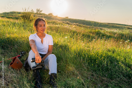 young beautiful woman is sitting in the grass, resting and enjoying the view