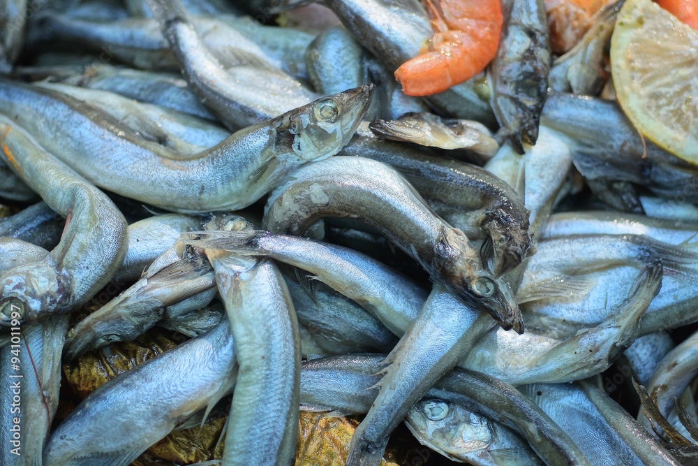 Fototapeta premium a pile of small grey sea fish and red boiled shrimps on the street