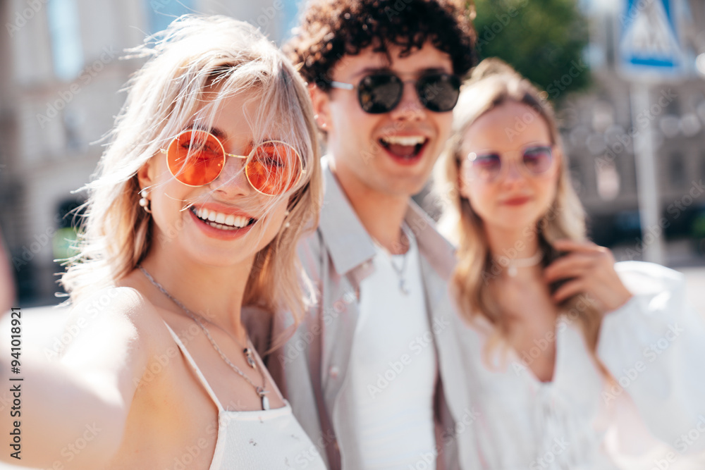 Young three stylish friends posing in the street. Fashion man and two cute female dressed in casual summer clothes. Smiling models having fun. Cheerful women and guy outdoors, in sunny day Young three stylish friends posing in the street. Fashion man and two cute female dressed in casual summer clothes. Smiling models having fun. Cheerful women and guy outdoors, in sunny day