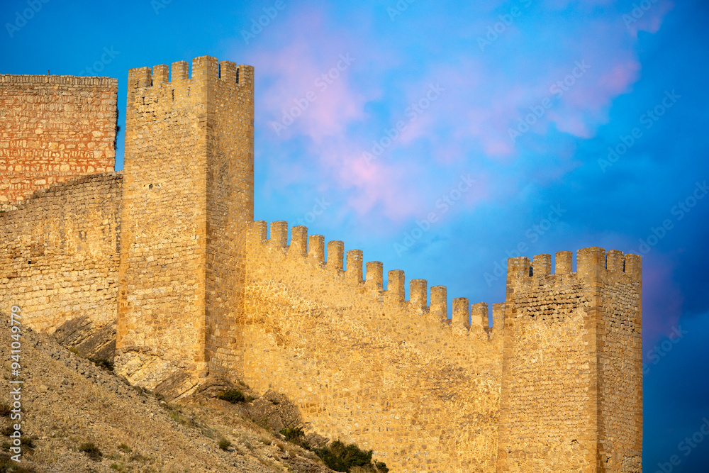 Naklejka premium Detail of the high crenellated towers and walls of the Albarracin castle fortress, Teruel, Aragon, Spain, with golden evening light