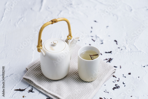 Tea concept with set of white tea cups and teapot on concrete background with copy space