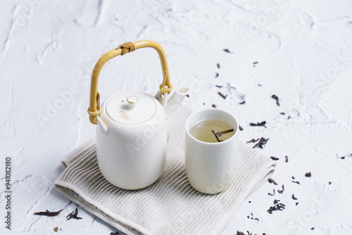 Tea concept with set of white tea cups and teapot on concrete background with copy space