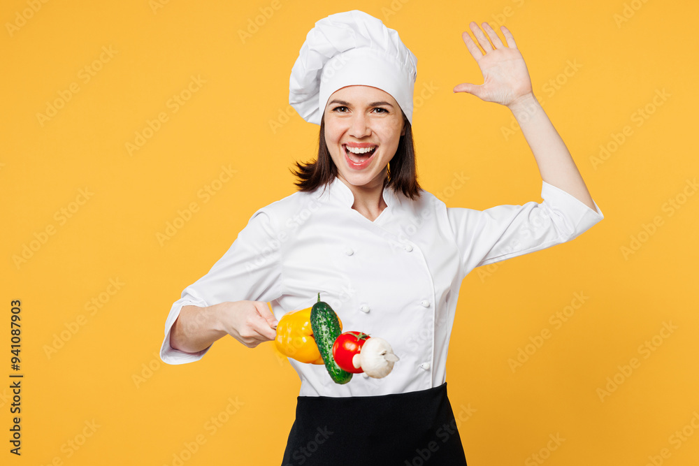 Young happy chef cook baker woman wear white shirt black apron uniform toque chefs hat hold roasted vegetables on skewer pov fighting isolated on plain yellow background studio. Cooking food concept. Young happy chef cook baker woman wear white shirt black apron uniform toque chefs hat hold roasted vegetables on skewer pov fighting isolated on plain yellow background studio. Cooking food concept.