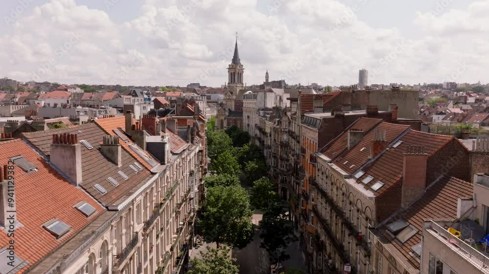 Charming Brussels street showcases delightful architecture, featuring an iconic church steeple that rises prominently against the skyline