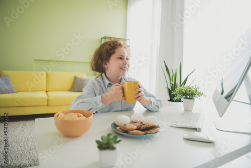 Photo of charming adorable girl schoolkid wearing uniform sitting chair drinking cacao remote education daylight indoors