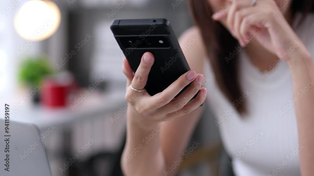 Businesswoman holds a smartphone while browsing online. Using her index finger, she navigates the screen, accessing various applications and information with ease Businesswoman holds a smartphone while browsing online. Using her index finger, she navigates the screen, accessing various applications and information with ease