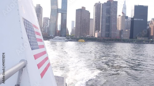 New York City skyline from ferry boat. Manhattan midtown highrise skyscrapers view from ferryboat. East river waterfront panorama, riverfront buildings architecture near water, USA. American flag. photo