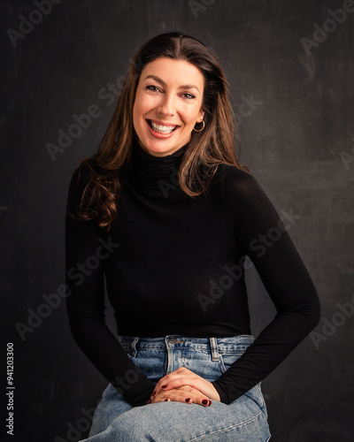 Close-up of an attractive brunette haired woman sitting against isolated dark background