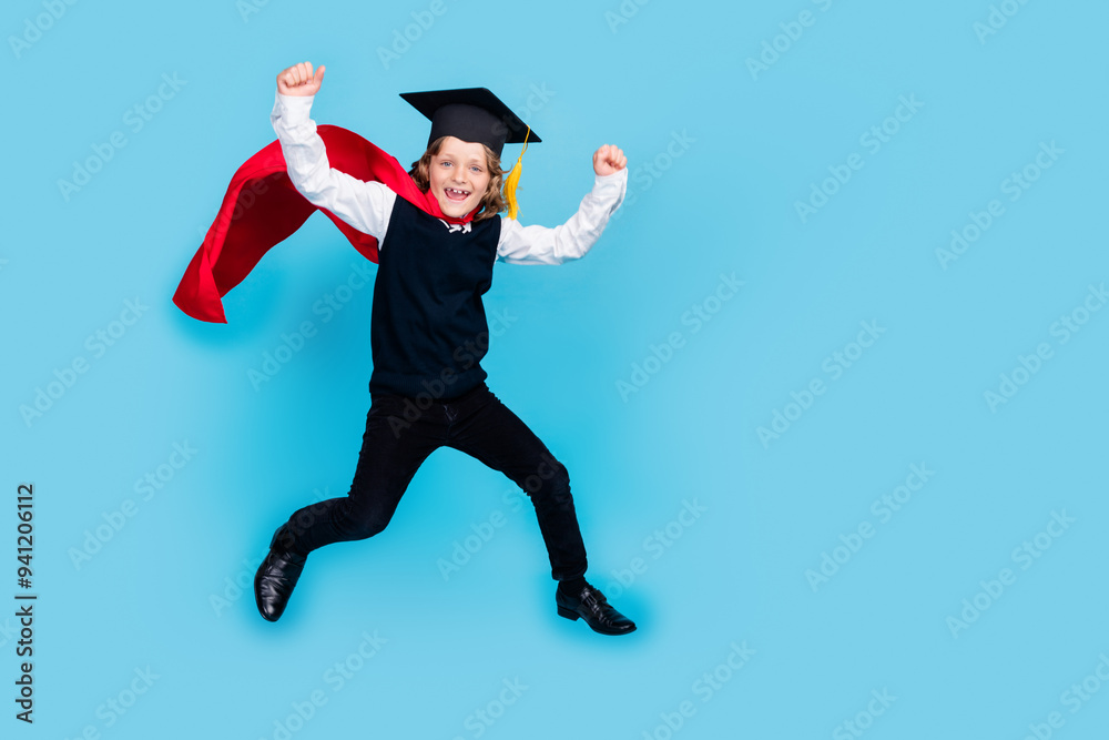 Full length portrait of little schoolchild boy wear uniform mortarboard cape jump isolated on blue color background Full length portrait of little schoolchild boy wear uniform mortarboard cape jump isolated on blue color background