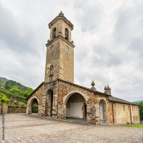 Ancient stone church with high tower and bell tower in the mountain village of Taramundi, Asturias.