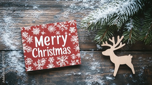 Merry Christmas card with snowflakes on a wooden surface, accompanied by a wooden reindeer and pine branches photo