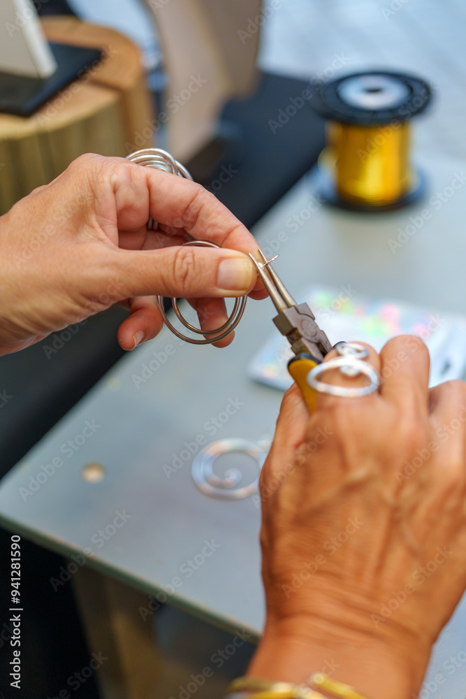 Fototapeta premium Unrecognizable Hispanic Woman in Her 50s Crafting Earrings at Her Street Stall Selling Handmade Aluminum Wire Jewelry 