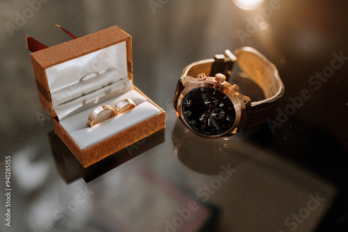 A watch and a ring are displayed in a box. The watch is a Rolex and the ring is a diamond band