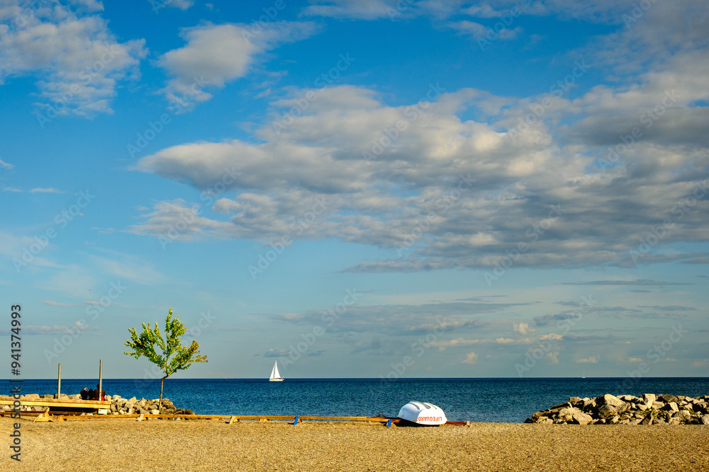 landscape with a white sailboat on horizon and white rowboat on beach lake ontario summer big sky room for text landscape with a white sailboat on horizon and white rowboat on beach lake ontario summer big sky room for text