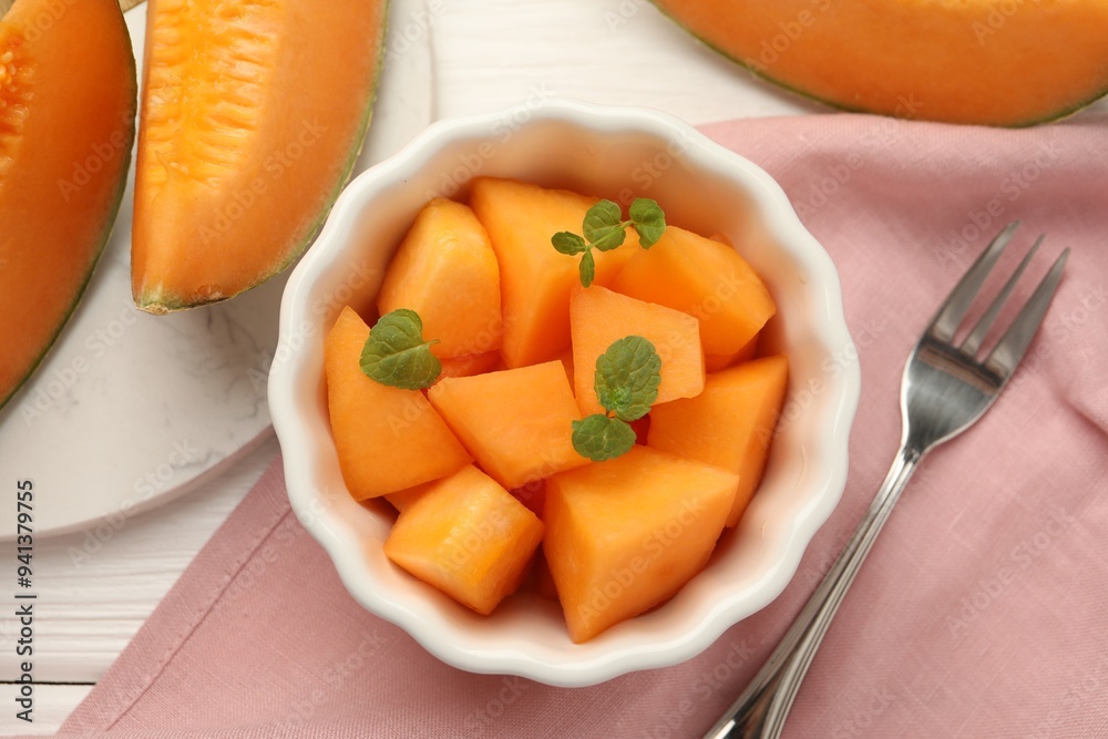 Pieces of ripe Cantaloupe melon in bowl and fork on white wooden table, flat lay Pieces of ripe Cantaloupe melon in bowl and fork on white wooden table, flat lay