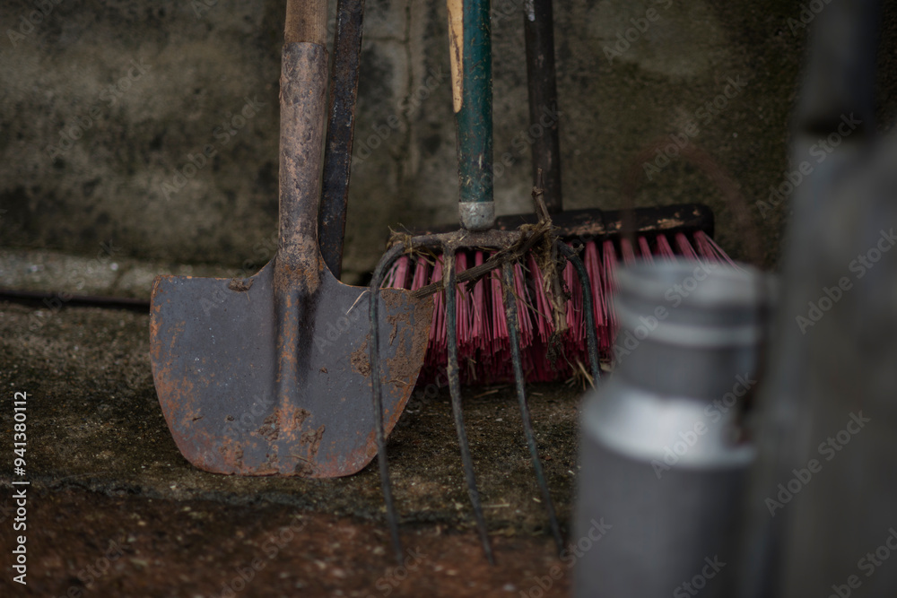 Spade, Fork and Brush. Fork, brush and round nosed spade against a farm wall with out of focus milk churns in the foreground. Spade, Fork and Brush. Fork, brush and round nosed spade against a farm wall with out of focus milk churns in the foreground.
