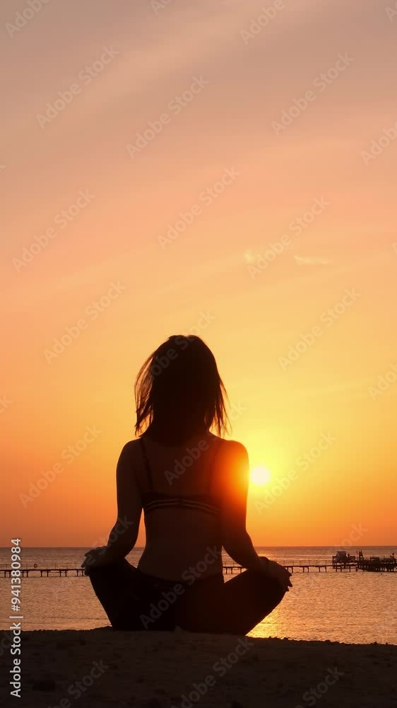 Vertical video: A serene silhouette of a slender woman meditating by the sea at sunset. Captures tranquility and inner peace, ideal for wellness and relaxation-themed ads. Vertical video: A serene silhouette of a slender woman meditating by the sea at sunset. Captures tranquility and inner peace, ideal for wellness and relaxation-themed ads.