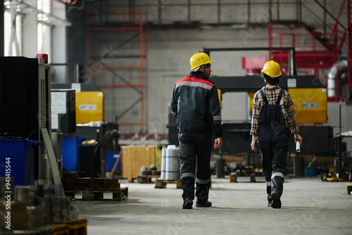 Engineers walking through industrial workshop, discussing current project and machinery
